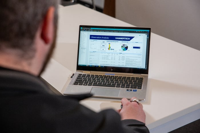 EHS worker looking at construction safety analysis on HammerTech Safety Platform at his desk.