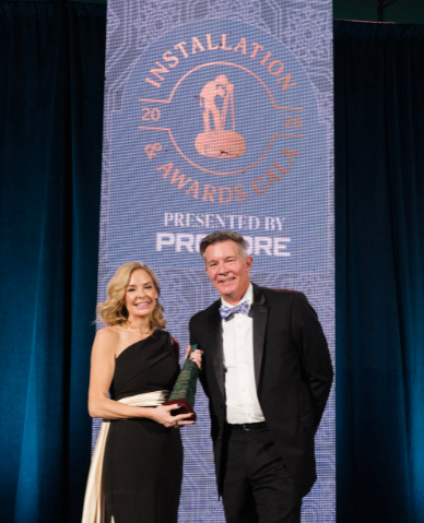 Melvina Stacey standing with  HammerTech CSO, Doug Rubingh at the 2026 AGC Installation and Awards Gala where she won the award she is holding in here hands