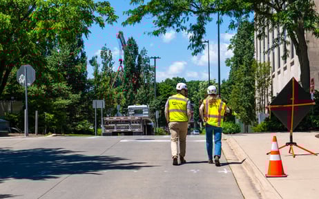 Two power construction contractors walking down the road chatting construction safety while wearing their PPE
