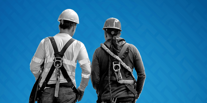 The back of two construction workers wearing harnesses after a safe day on site using HammerTech construction safety software.