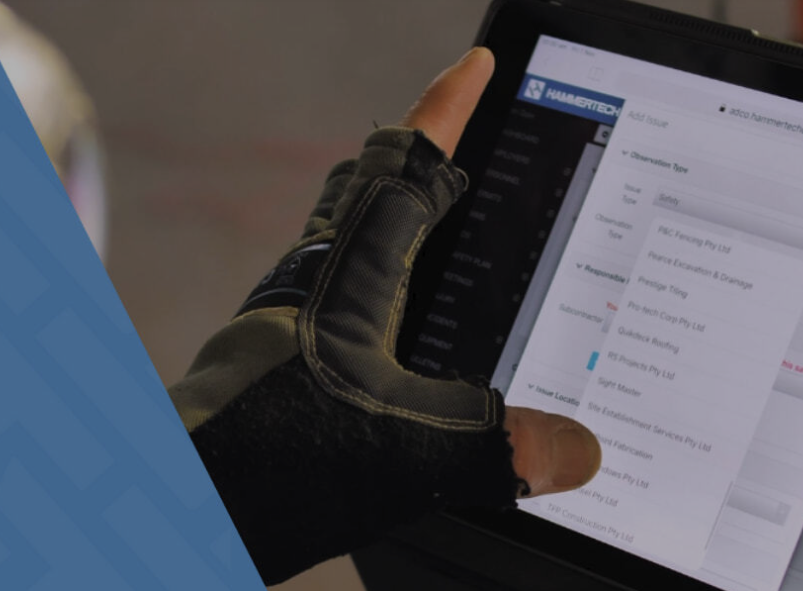 Image of a construction worker holding a tablet with HamemrTech's construction safety software platform showing.