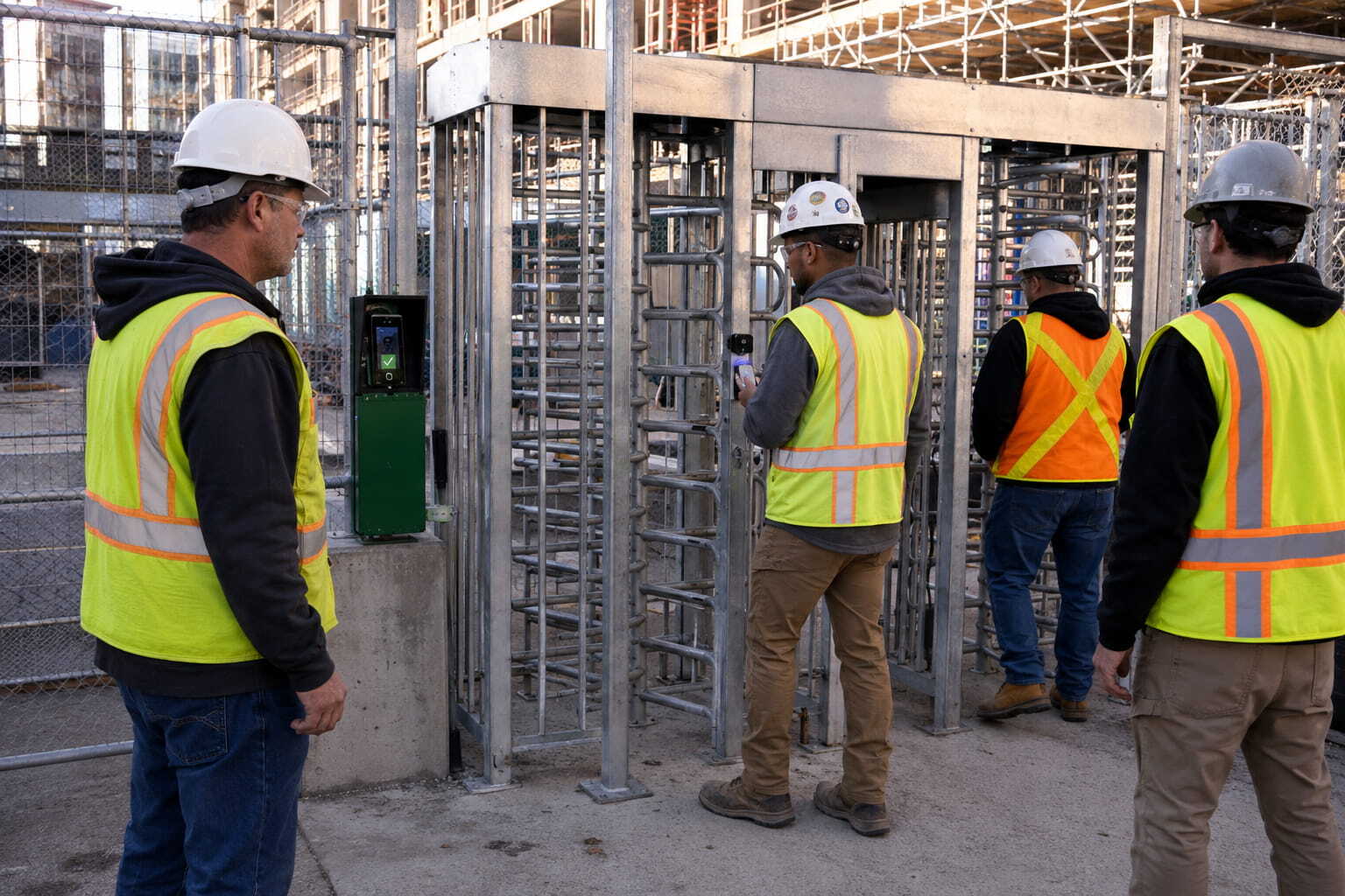 wide shot of the three workers walking through the turnstile on active jobsite using HammerTech construction safety software and irongate solutions.