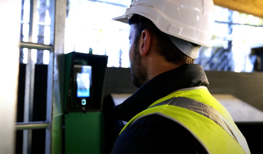 Close-up image of a construction worker with a hard hat on, scanning face with facial recognition for site access control in UK and Europe. 