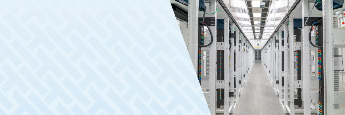 A long corridor inside a data center with rows of white server racks on both sides, viewed from the center aisle, with a light blue geometric overlay on the left side of the image.