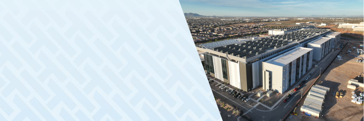 Aerial view of a large industrial data center facility with multiple buildings and rooftop equipment, set beside a suburban area, with a light blue geometric overlay on the left side.