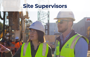 Image of two site supervisors on a job site looking to the left, wearing reflective vests, and with heavy equipment behind them.