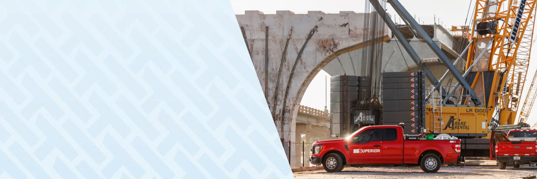 Red Superior Construction pickup and crane at a concrete bridge construction site.